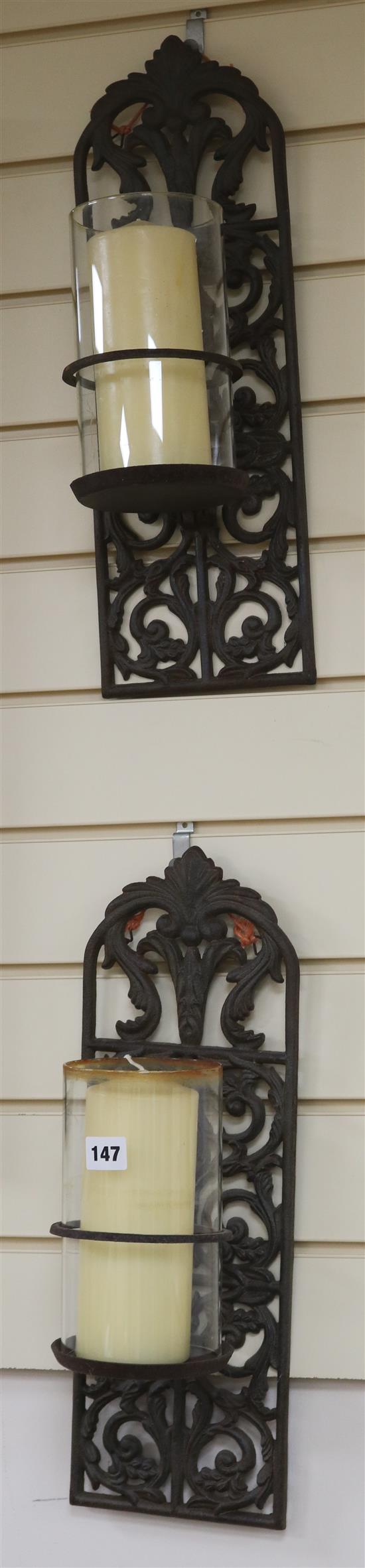 A pair of cast iron wall sconces with candles
